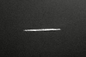 Line of cocaine on dark background, top view