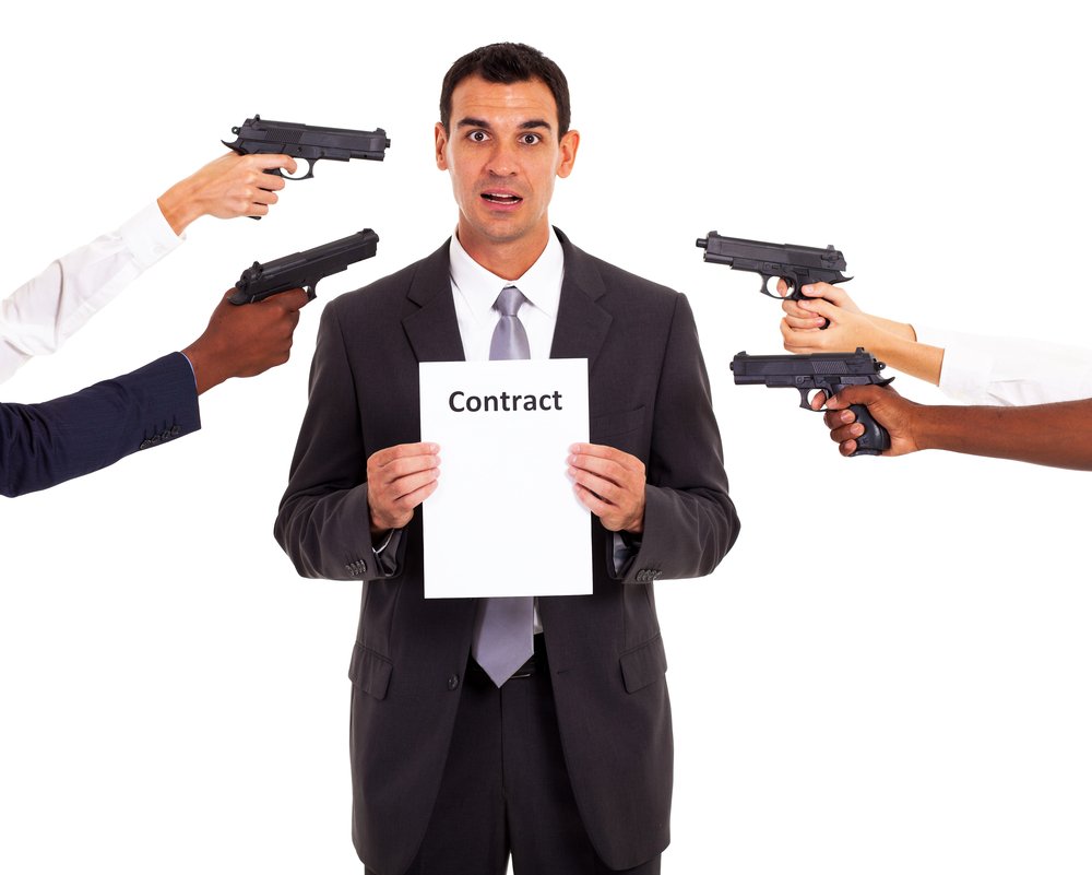 Man holding contract while multiple guns are pointed at him.