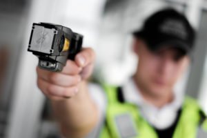 Police officer pointing a stun gun.