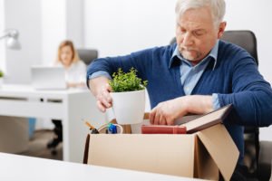 Trabajador despedido limpiando el escritorio después de ser objeto de represalia ilegal por presentar una reclamación de compensación laboral