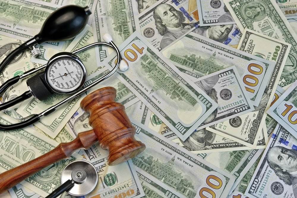 Dinero, un martillo y un estetoscopio de médico para ilustrar el fraude en el sector de la salud