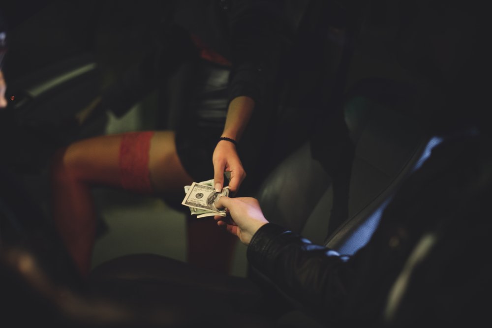Una prostituta recibiendo dinero como ejemplo de una violación del Código Penal de California 647b PC