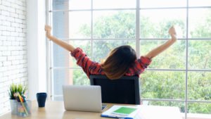 Woman at desk stretching during a rest break from work