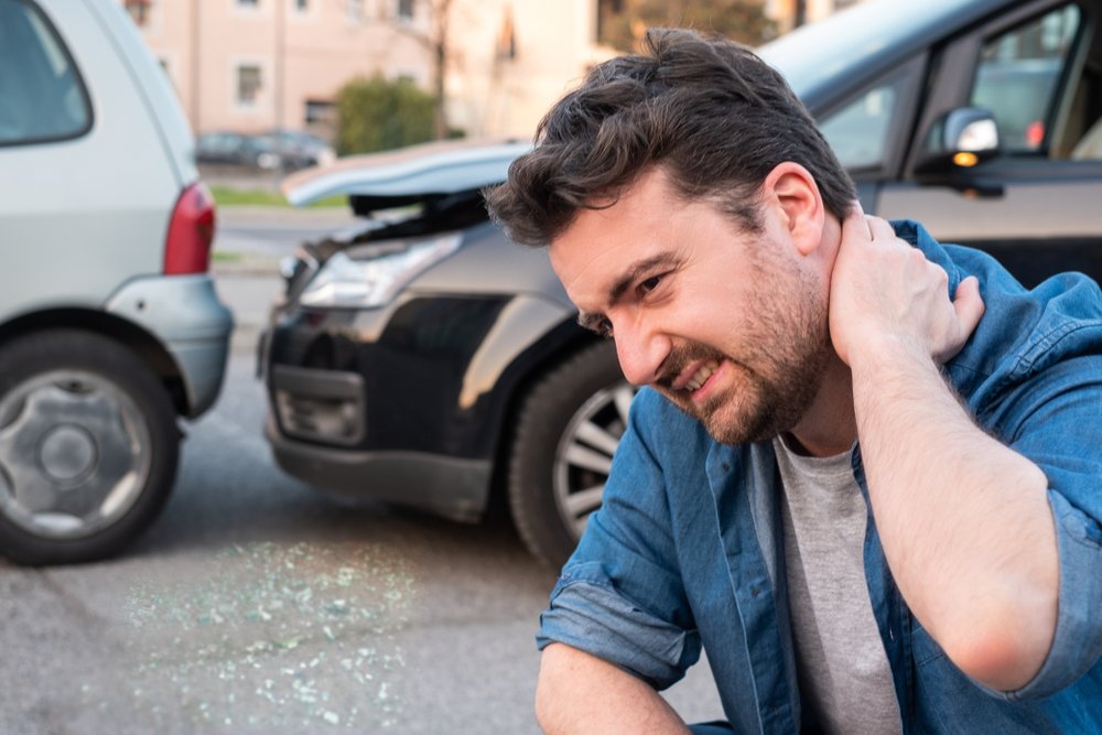 A passenger holding his neck in pain after a Lyft accident.