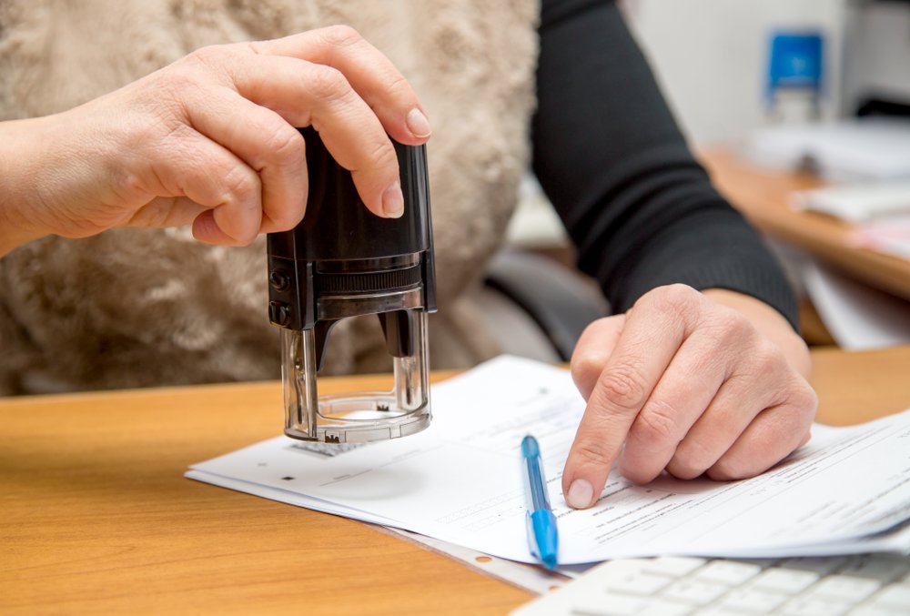 A woman stamping a document - forging or counterfeiting a public seal is a crime in California