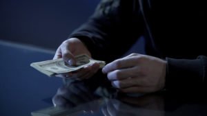 Close-up of scammer's hand about to deposit "dirty money" in violation of federal money laundering laws in Nevada