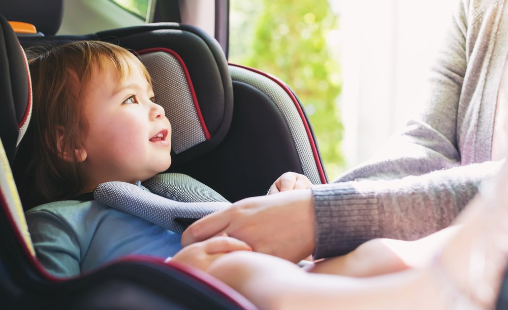 A young child being buckled into a child seat.