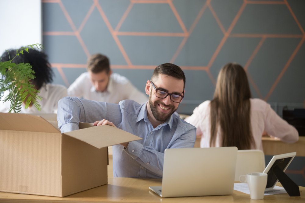 Un empleado desempaquetando alegremente sus cosas en el trabajo.