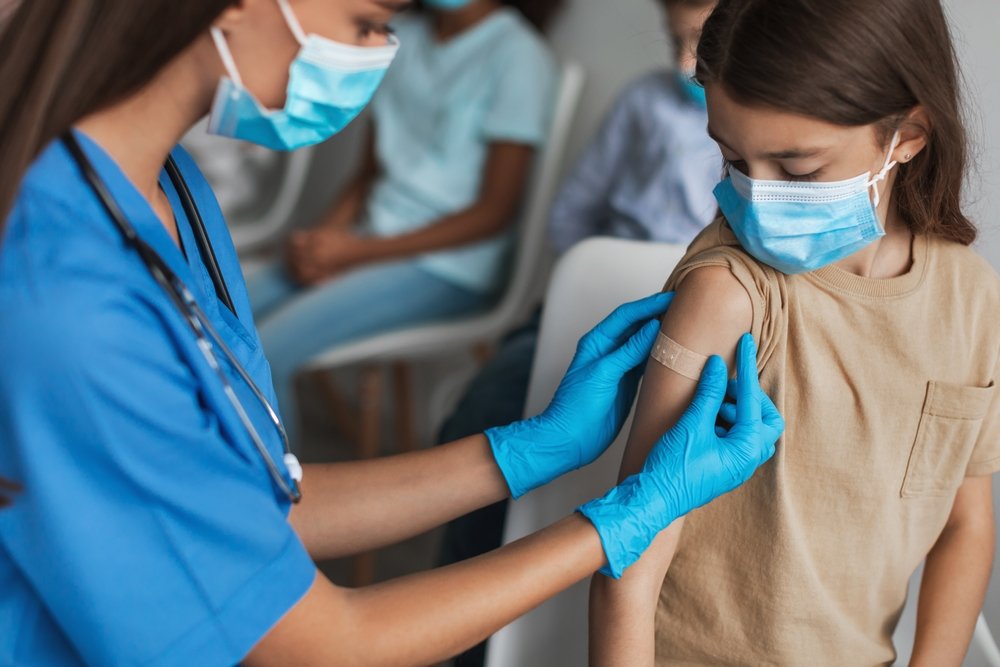 A nurse applying a bandage to the arm of a young child.