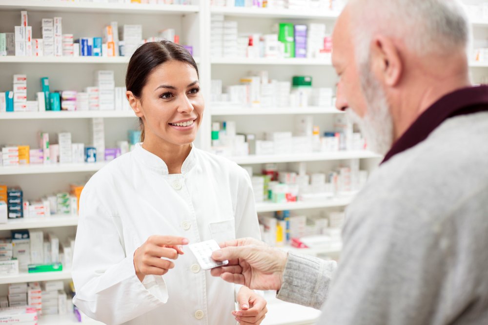 A pharmacist handing a patient his medicine.
