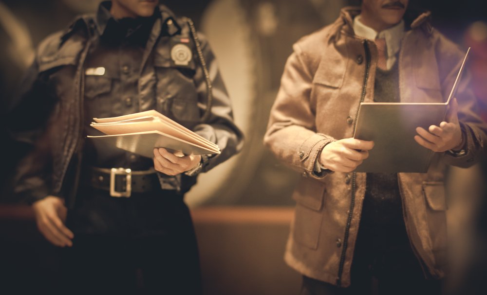 A police officer and a detective reviewing documents.