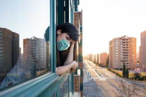 A woman confined to her home, staring out the window.