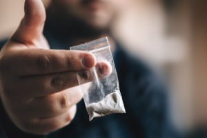 Hand holding baggie of cocaine in drug sale
