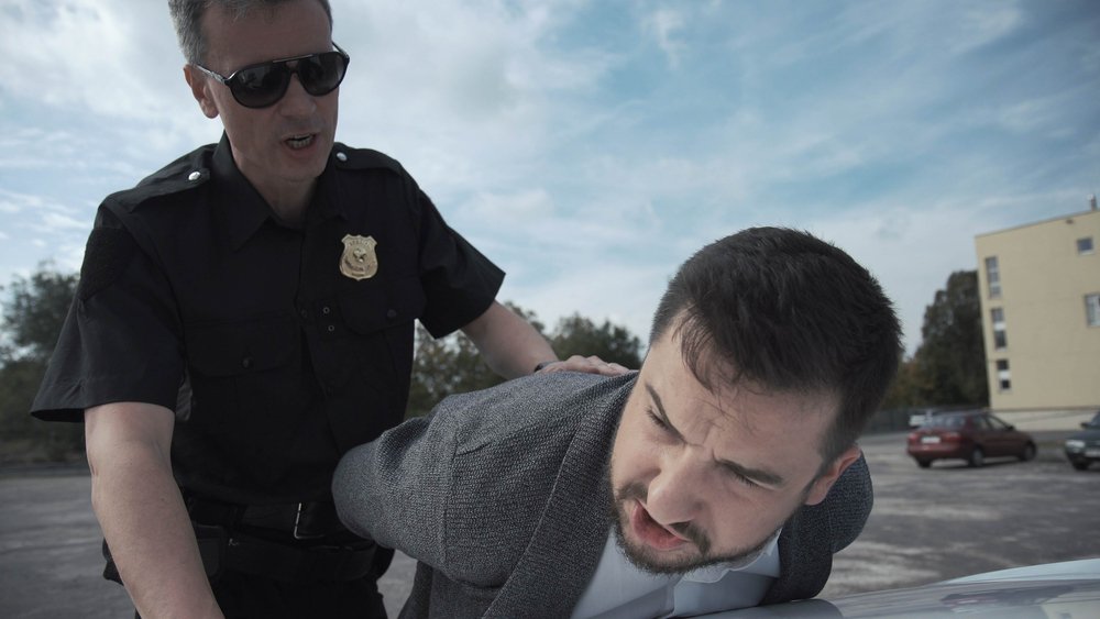 A police officer pushing down a man on top of a car. Our California police misconduct attorneys help victims to bring civil rights lawsuits.