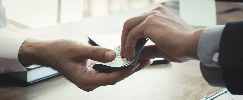 Money changing hands over a work desk.