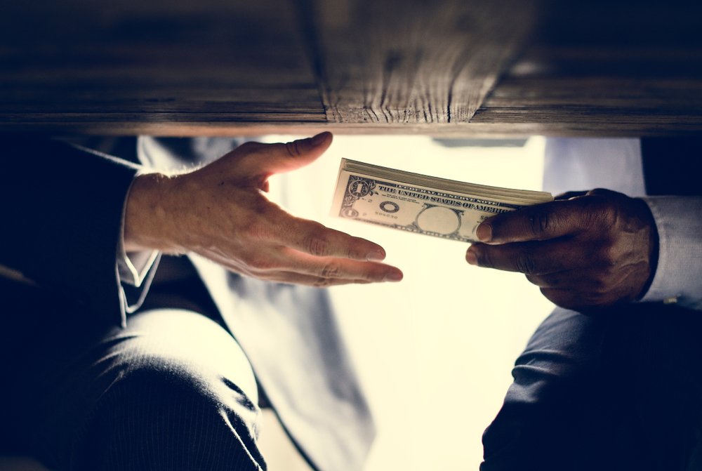 Money being exchanged under a table.