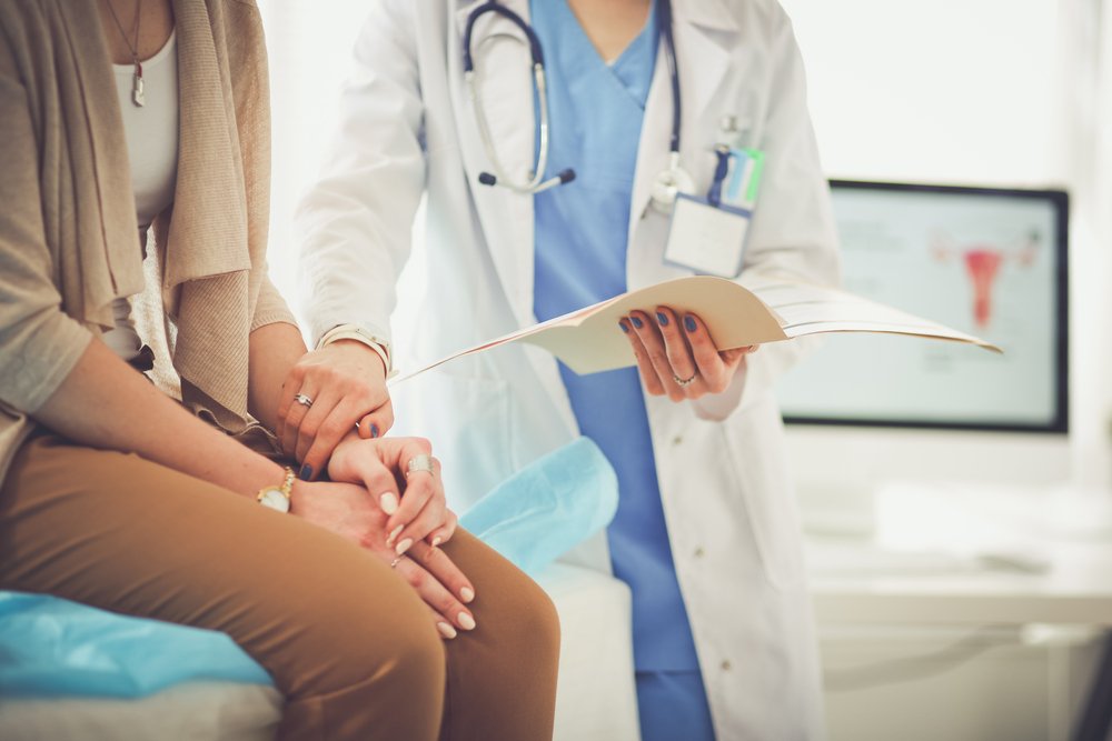 Una doctora parada junto a su paciente.