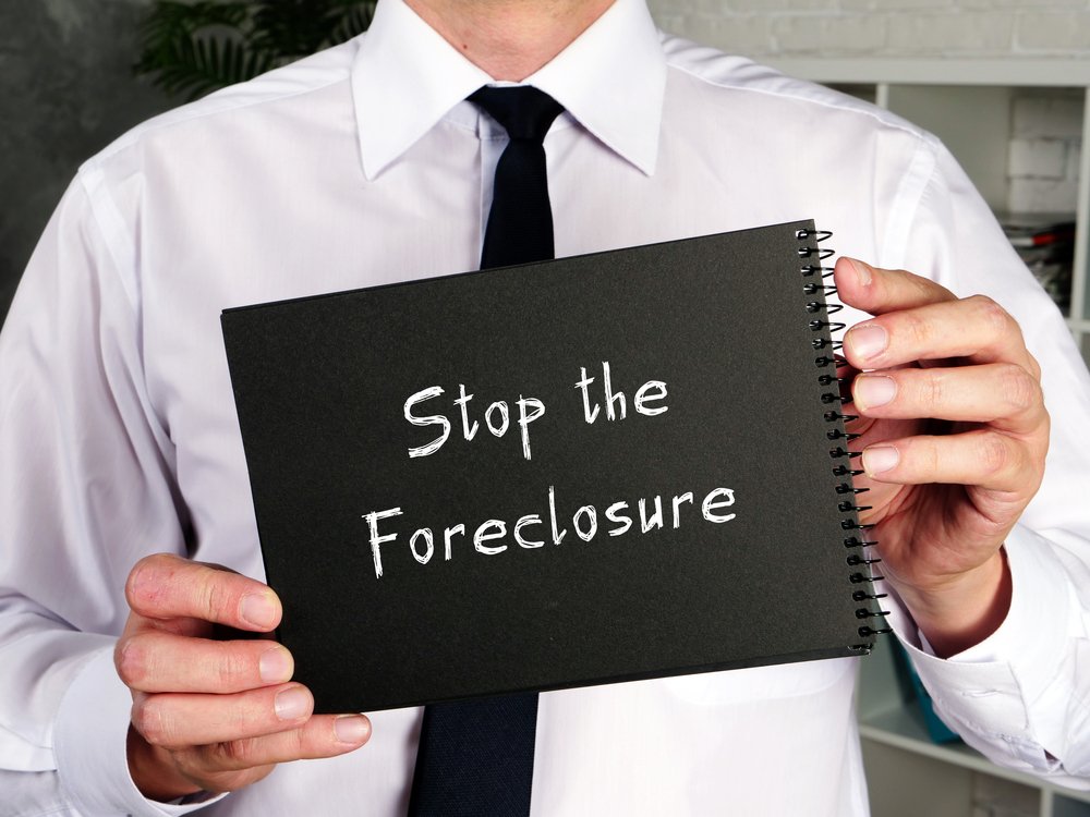 A foreclosure consultant holding up a sign.