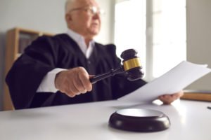 A judge holding motion documents with a gavel in his hand.