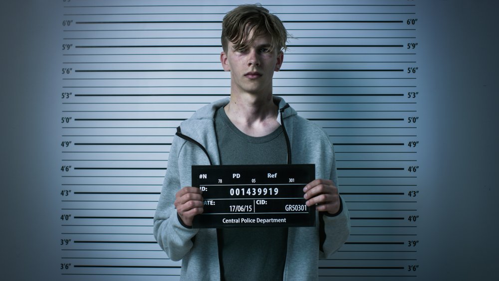 A teenage boy having his mugshot taken.