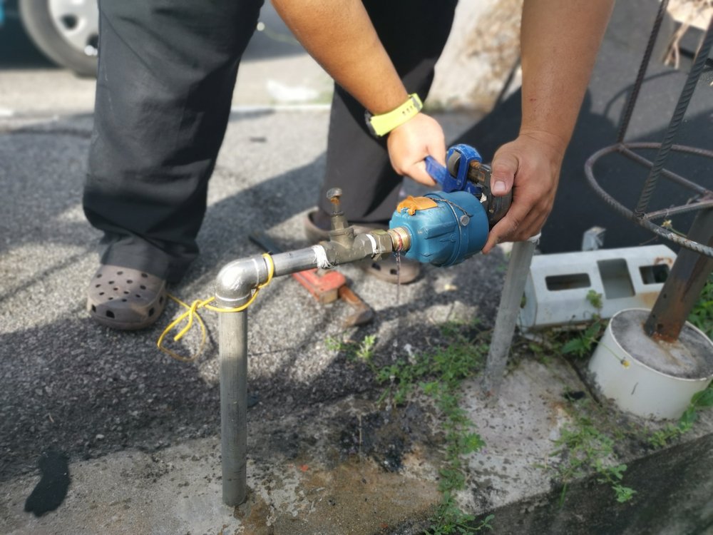 A man disconnecting a water line.