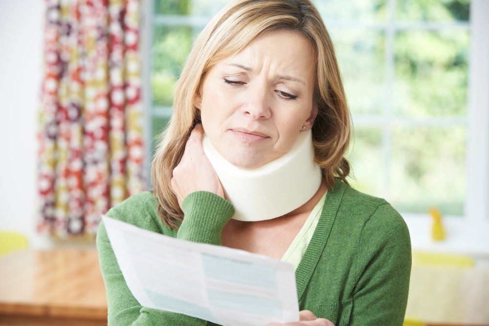 A woman applying pressure to her neck brace that she possibly received to help her neck ache after a bad car accident.