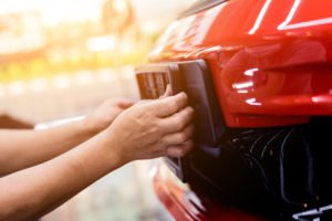 Man affixing plates to car