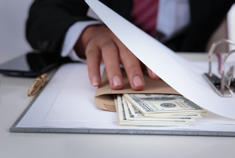 A person opening up a folder filled with money, potentially a bribe.