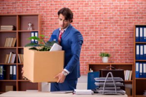 A man leaving his previous job with a box filled with his belongings.