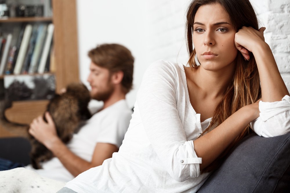 A woman looks unhappy as her husband pays more attention to their dog than her.