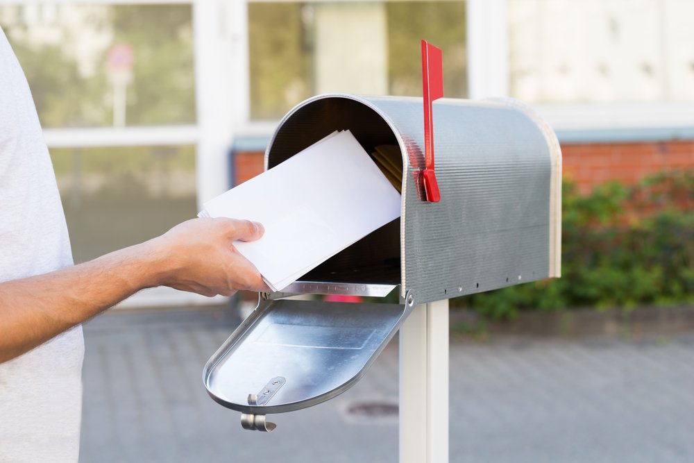 A man taking mail out of his mailbox.