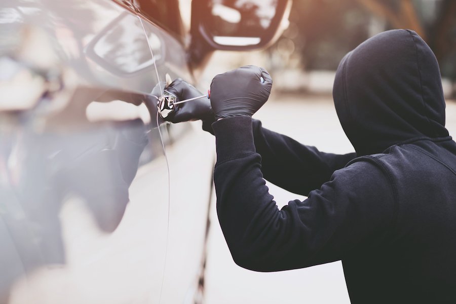 Hooded man breaking and entering into a car