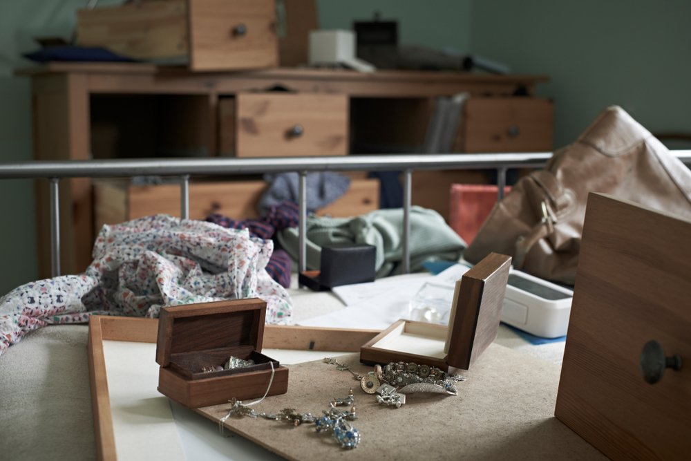 A ransacked bedroom with various pieces of jewelry strewn on the counter.