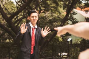 A young man raising his hands in fear while being pointed at in an apparent, possibly false, accusation.