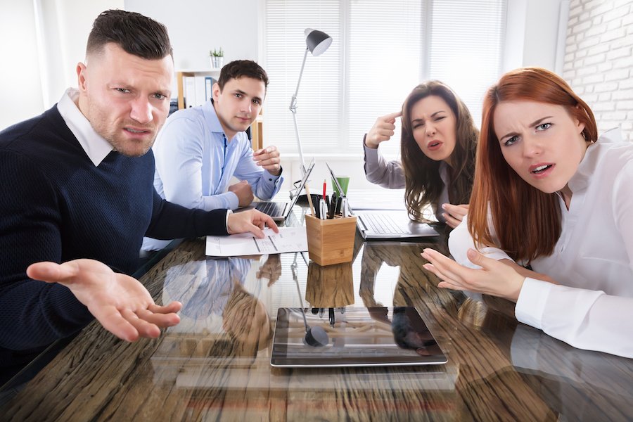 Cuatro compañeros de trabajo enojados y acosadores creando un ambiente laboral hostil