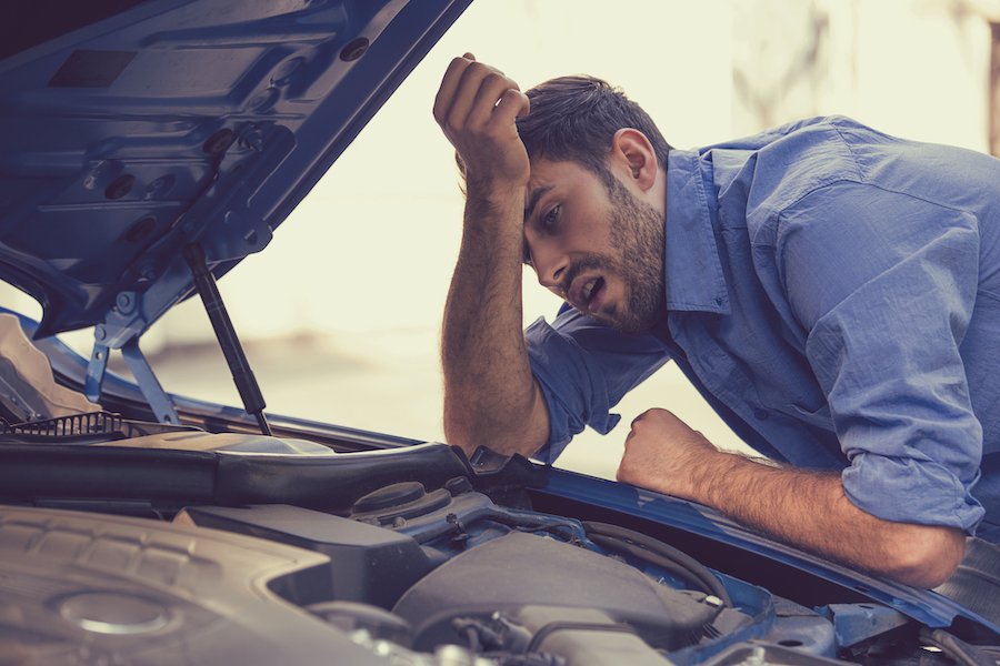 Man looking under the hood of lemon car