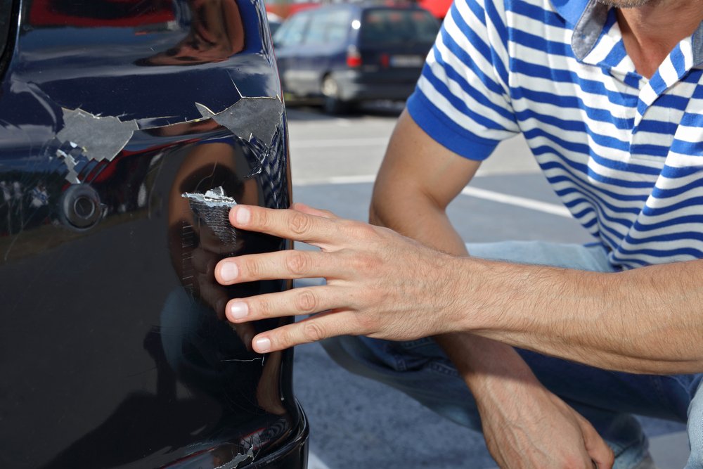 A man pointing out the damage caused by a parking lot accident.