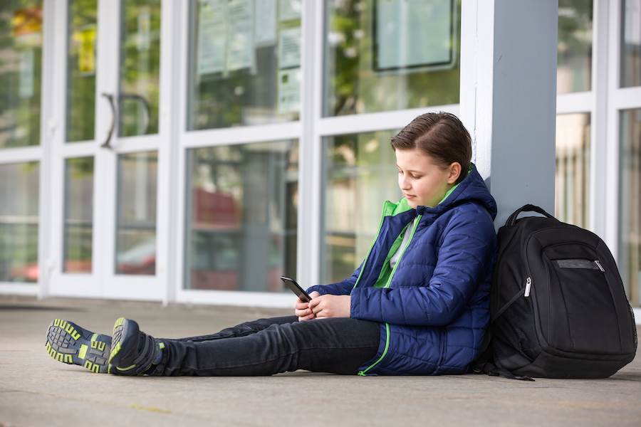 Teen boy on phone ditching school