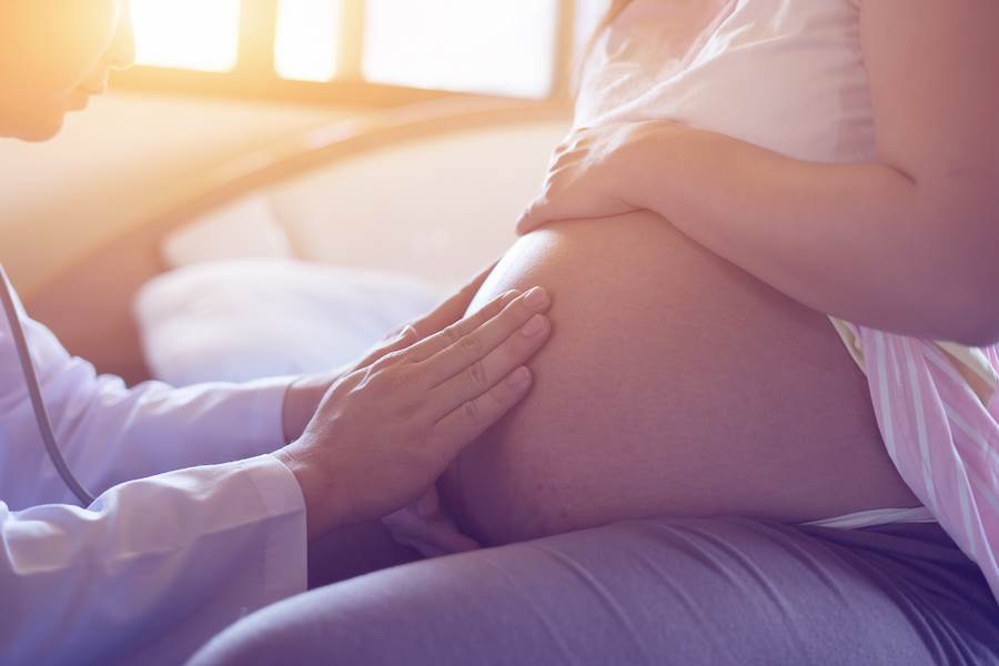 Doctor examining a patient's pregnant belly