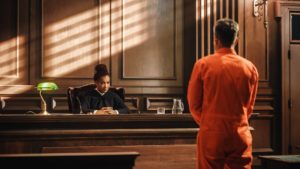 Hombre en traje de color naranja frente al juez en audiencia de fianza