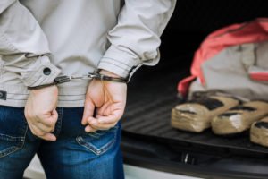 Hombre esposado por maletero de coche con drogas empaquetadas