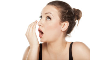 A woman exhaling into her hand to see if she can smell alcohol in her breath.