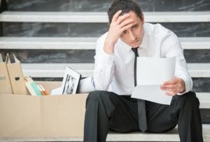 Fired frustrated man in suit sitting at stairs in office.