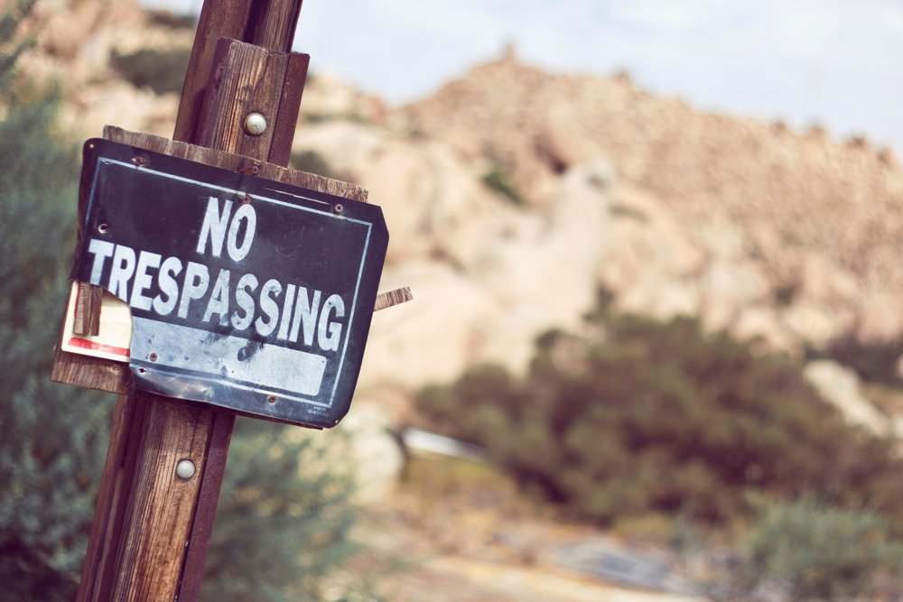 A "no trespassing" sign upon the entrance of a property, possibly in California.