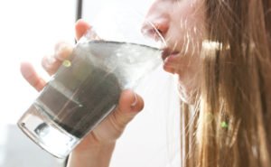 Woman drinking dirty water from glass cup