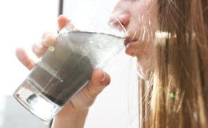 Woman drinking dirty water from glass cup