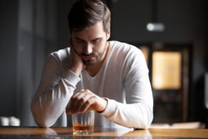 A man holding an alcoholic beverage sad that a DUI conviction has limited his job opportunities.