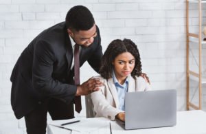 A woman being sexually harassed by a male colleague at work.