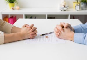 A couple negotiating a divorce with their wedding rings between them