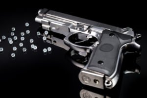 Gun with bb pellets against black background